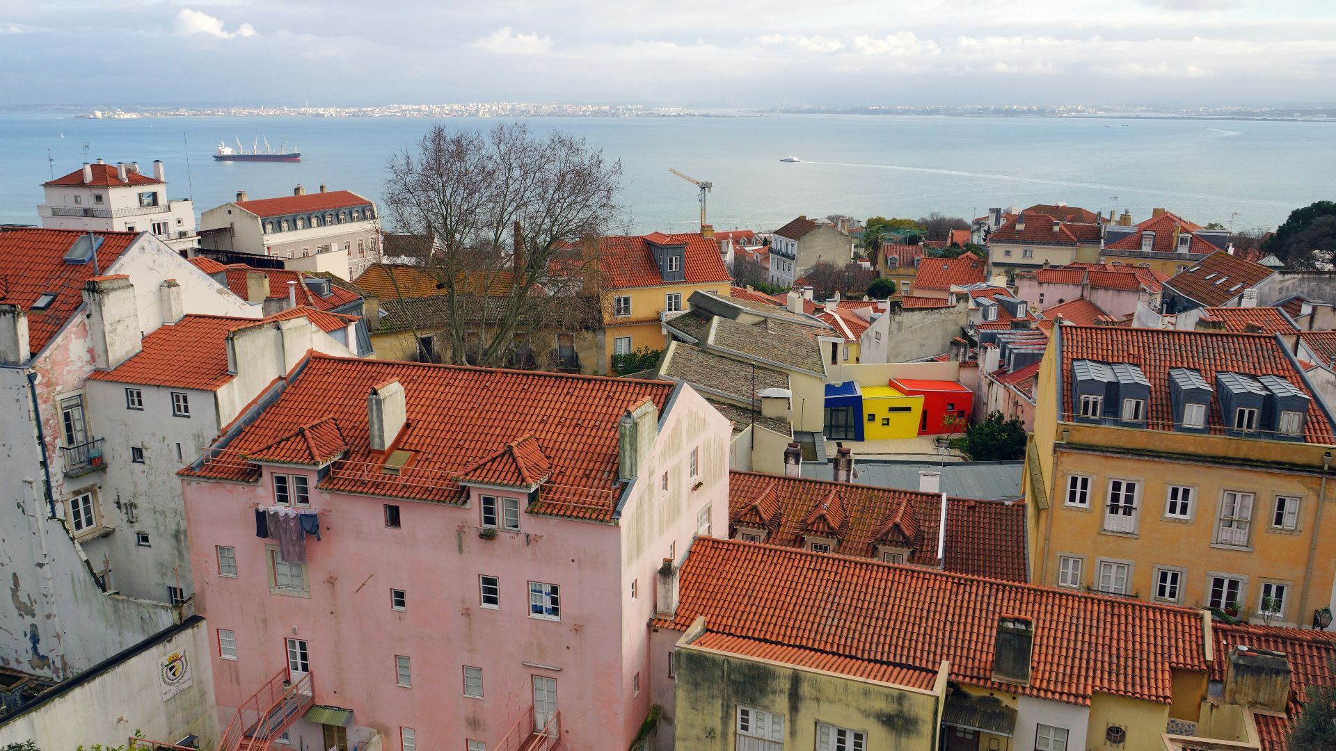 a group of buildings with red roofs and a body of water in the background