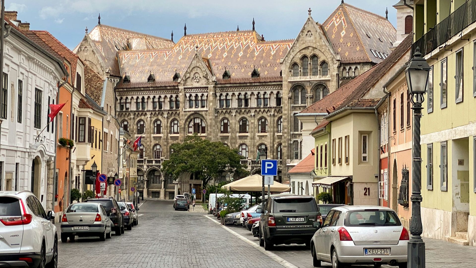 a street lined with parked cars next to tall buildings