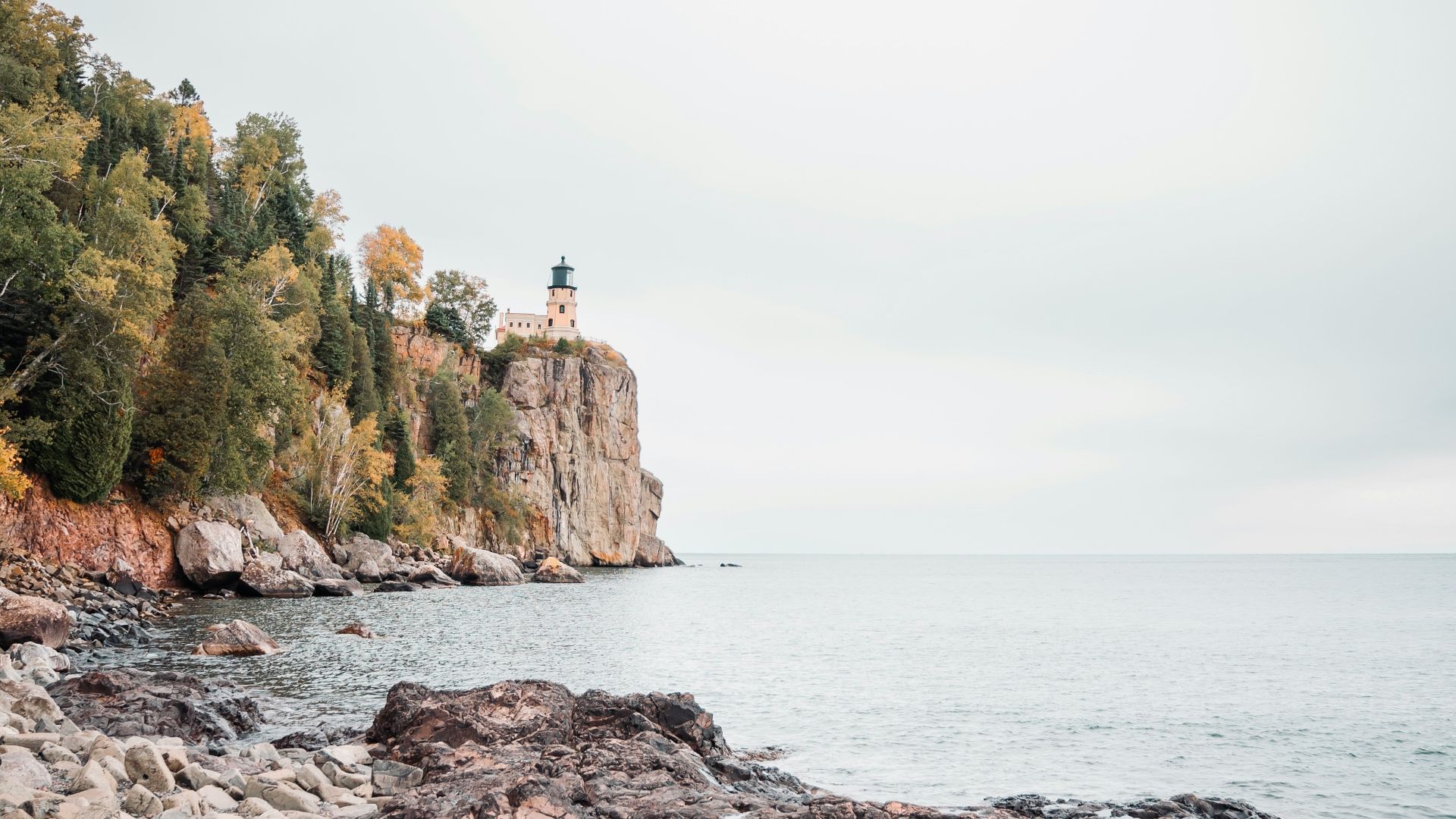 a rocky shore with a lighthouse in the distance