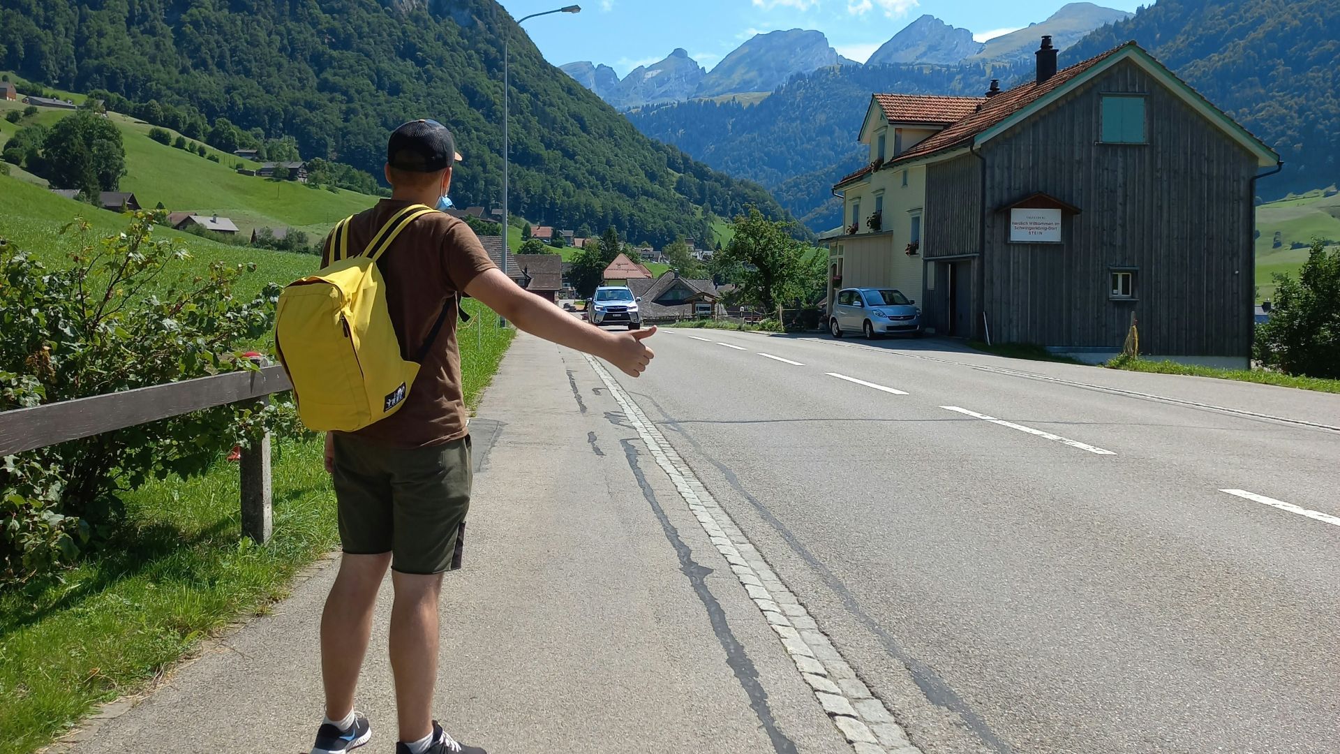 a man with a yellow backpack standing on the side of a road
