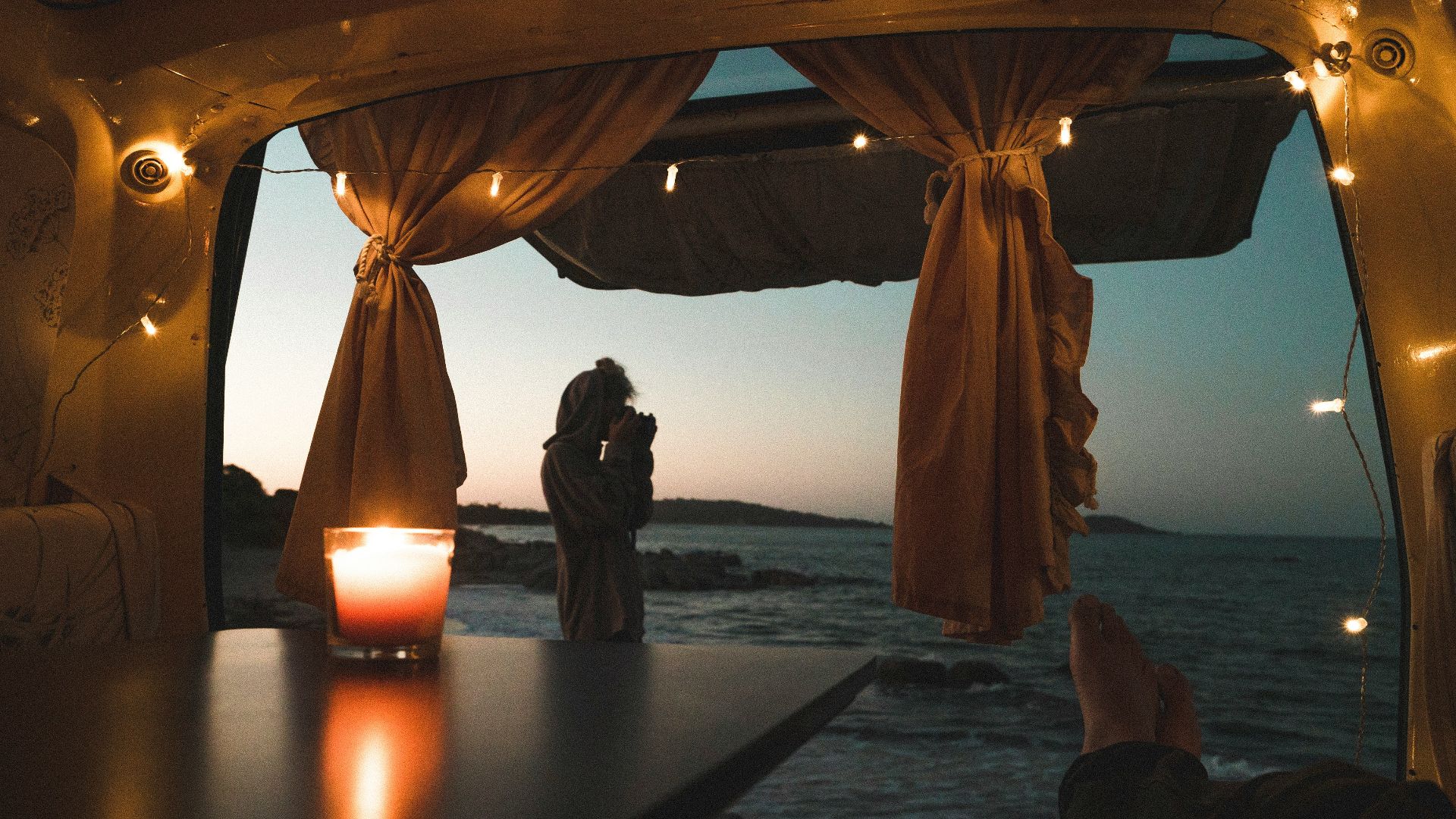 person lying on couch with body of water view at dusk