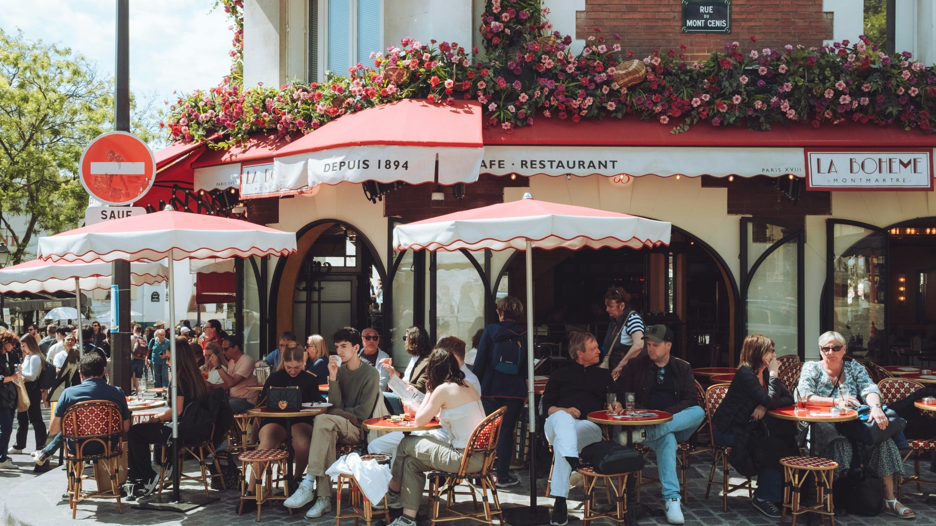 a group of people sitting at tables outside of a restaurant