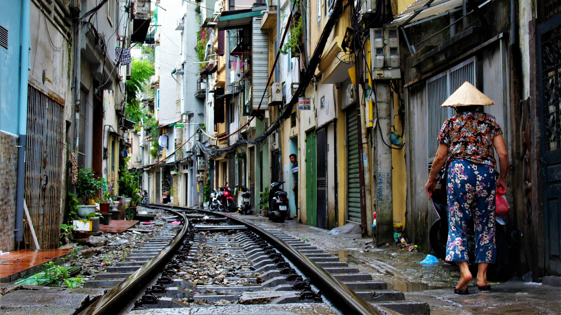 person walking on railway side between buildings at daytime