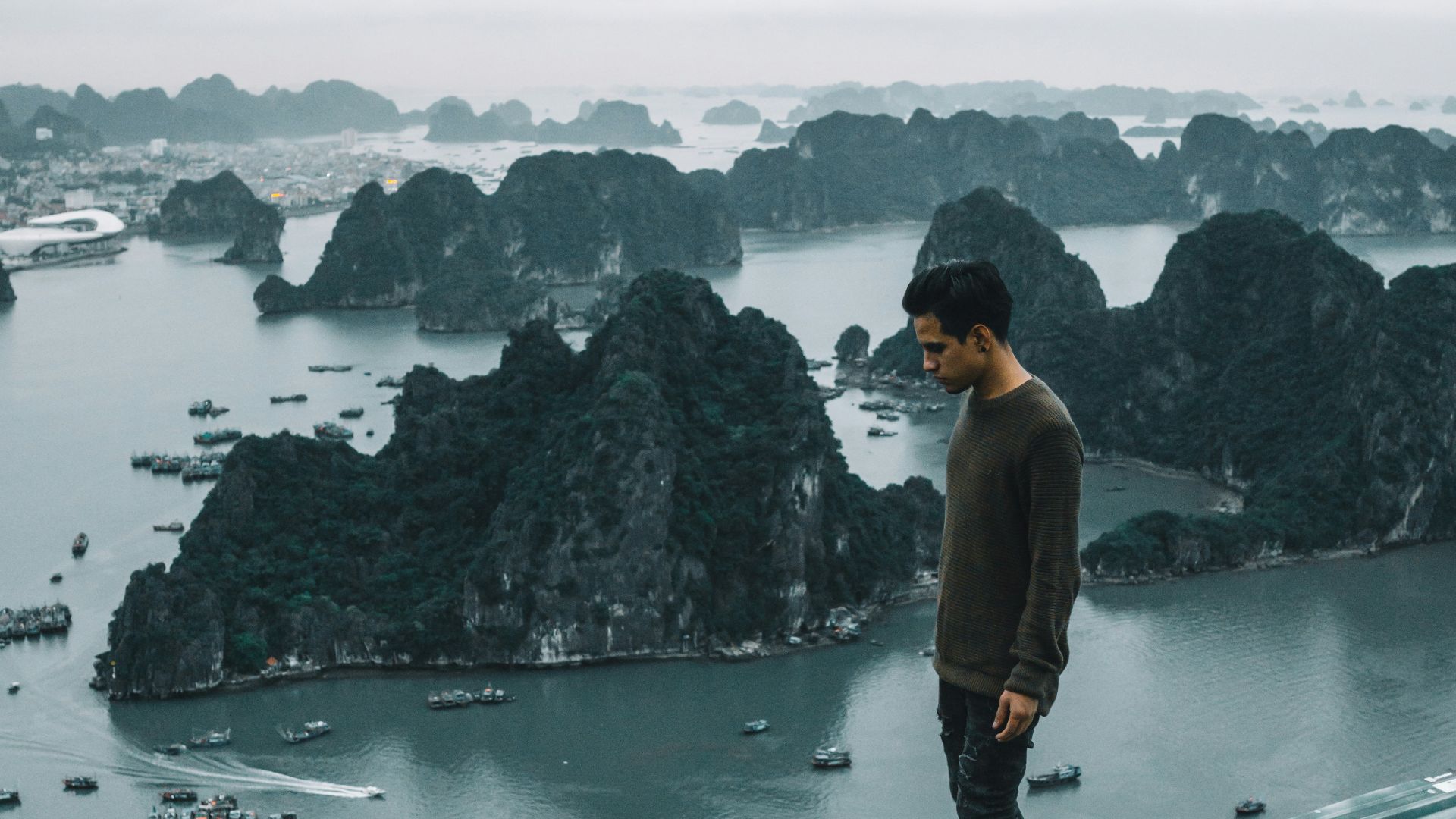 man wearing gray sweater standing on rooftop