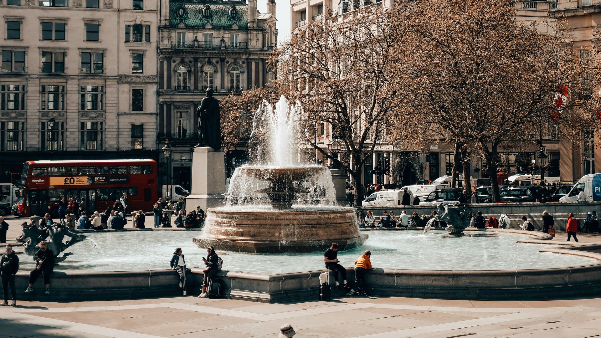 a man sitting on a bench in front of a fountain