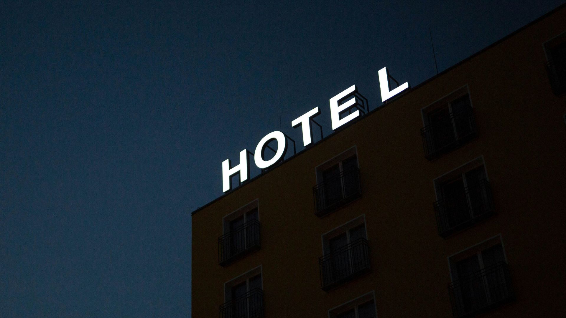 low-angle photo of Hotel lighted signage on top of brown building during nighttime