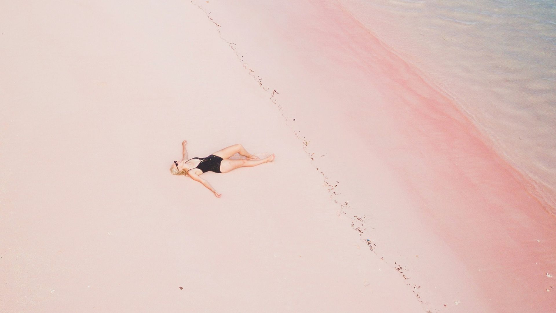 a woman laying on a beach next to a body of water