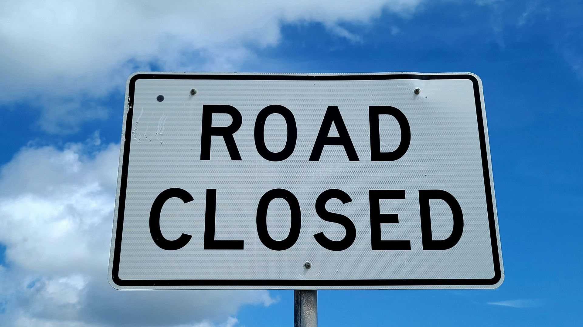 a road closed sign in front of a blue sky