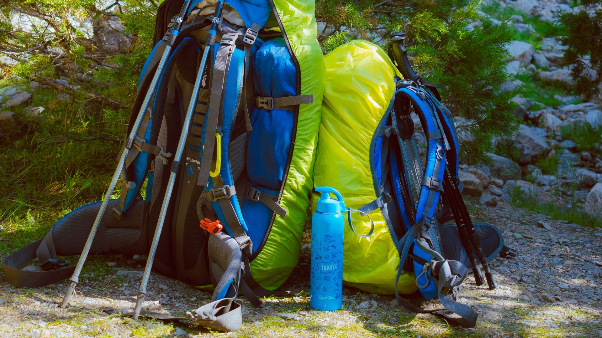 blue and black hiking backpacks on gray rocky ground