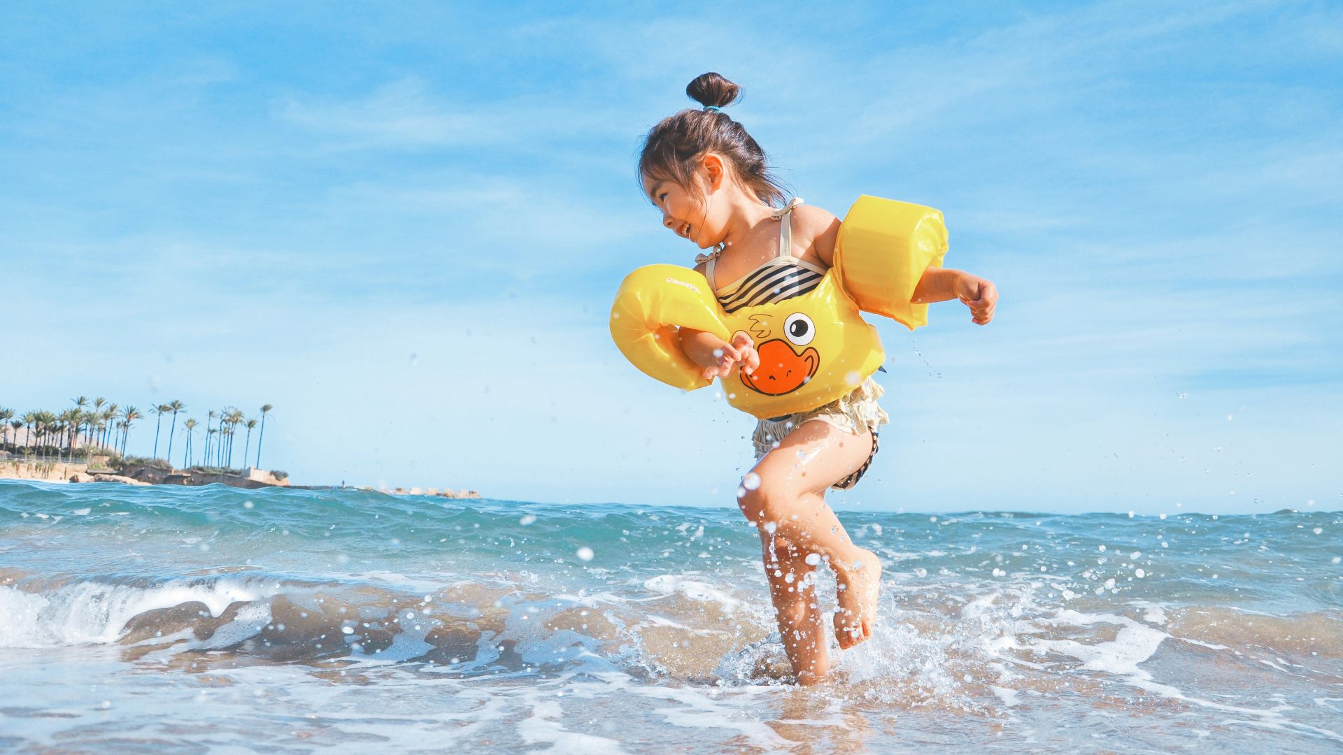 girl playing beside body of water during daytime