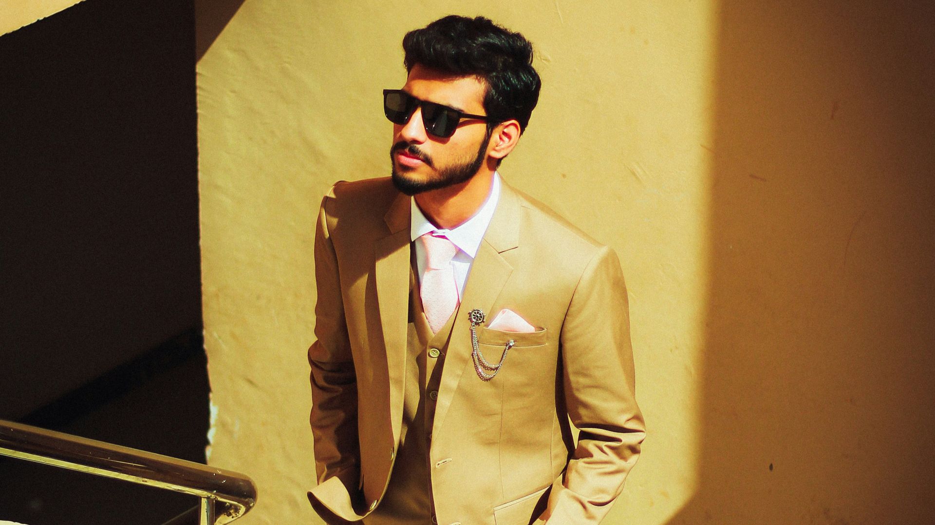 a man wearing a tan suit and sunglasses