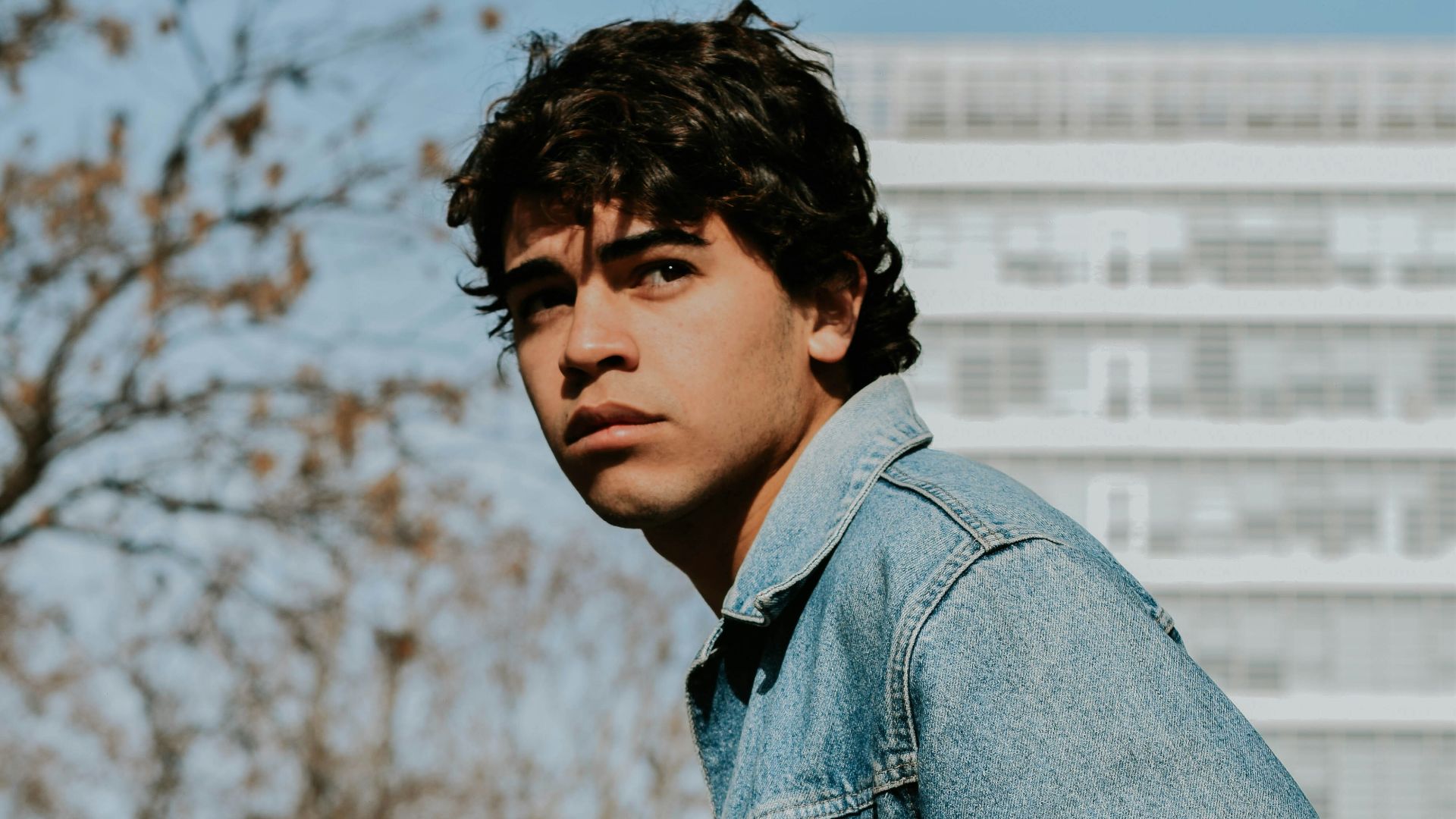 man in blue denim jacket sitting on black chair