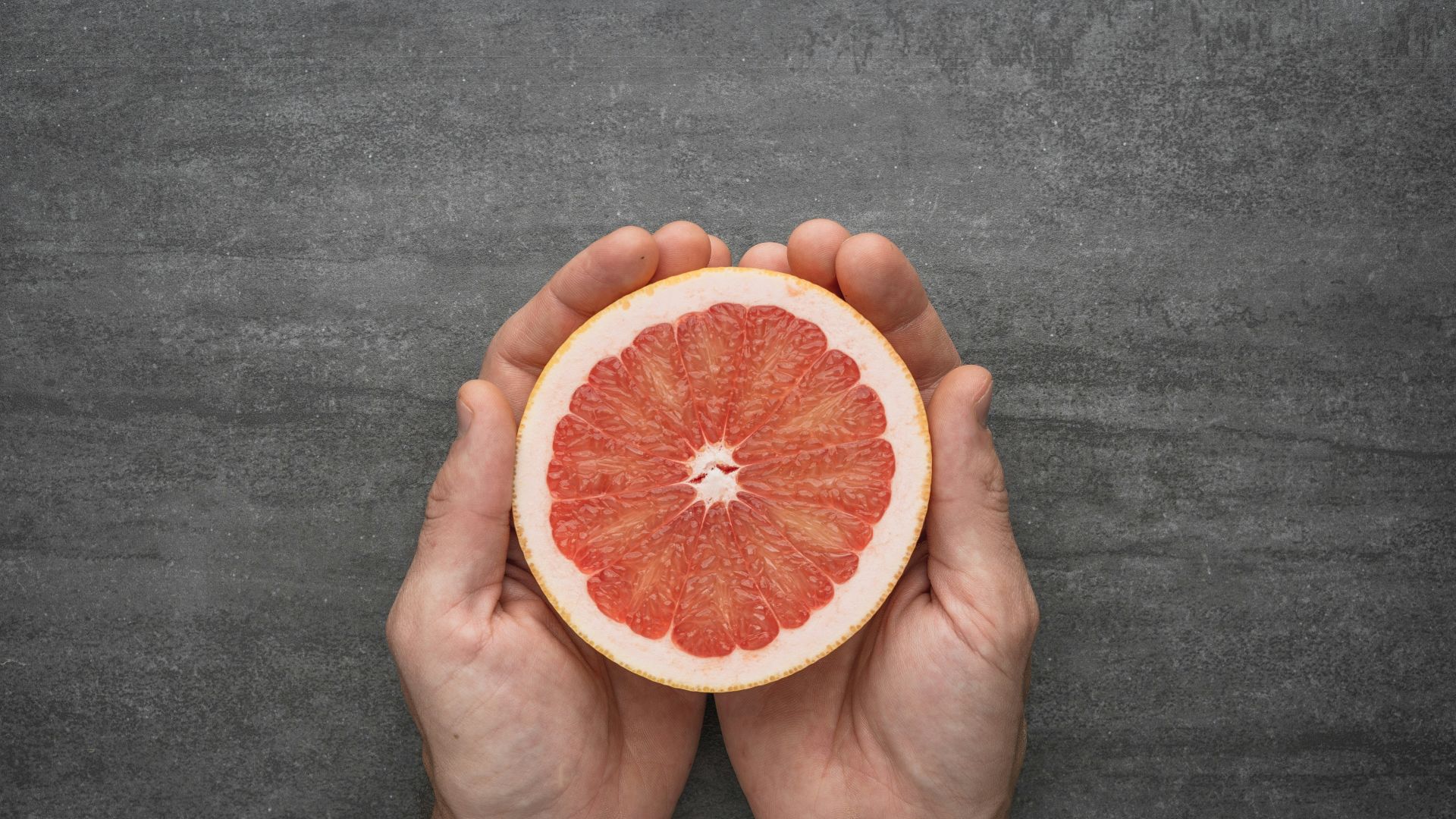 person holding orange citrus fruit