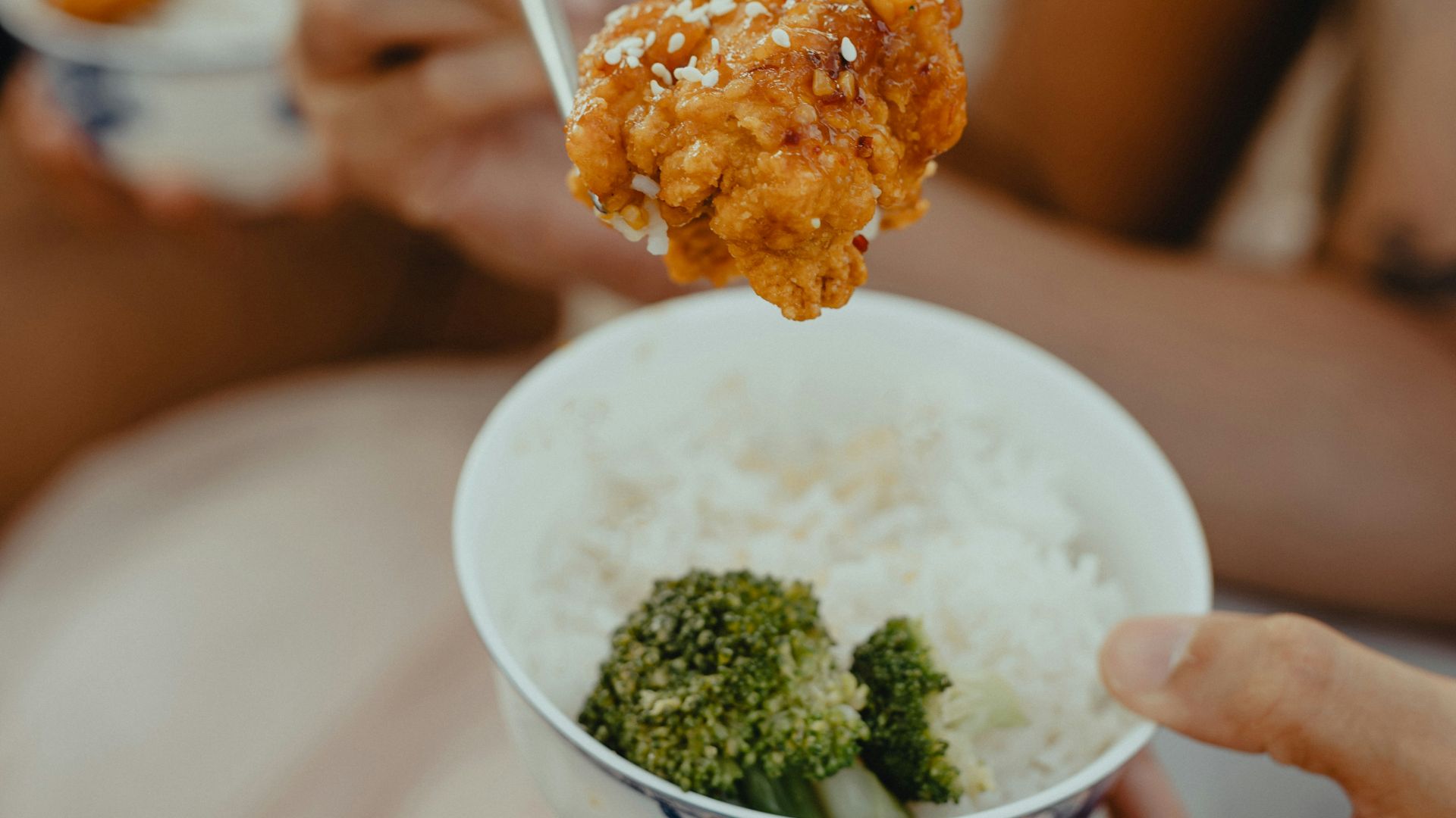 woman in white tank top holding spoon with rice