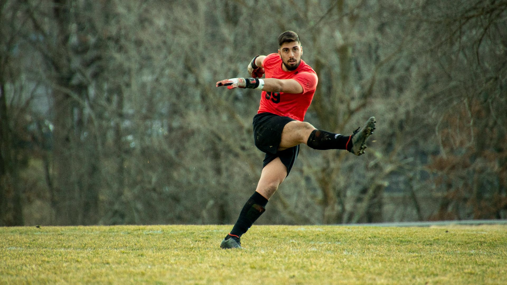 woman in red shirt and black shorts running on green grass field during daytime