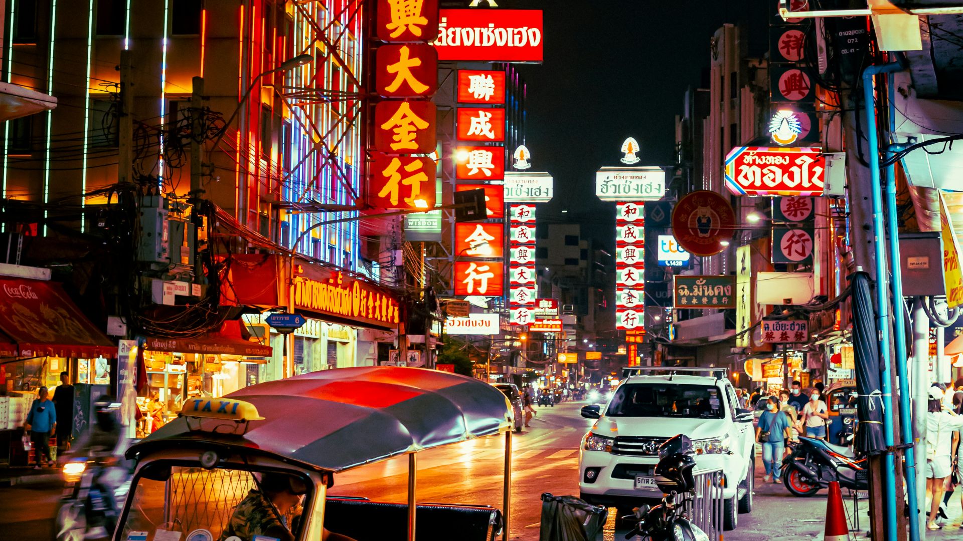 a street with neon signs and scooters