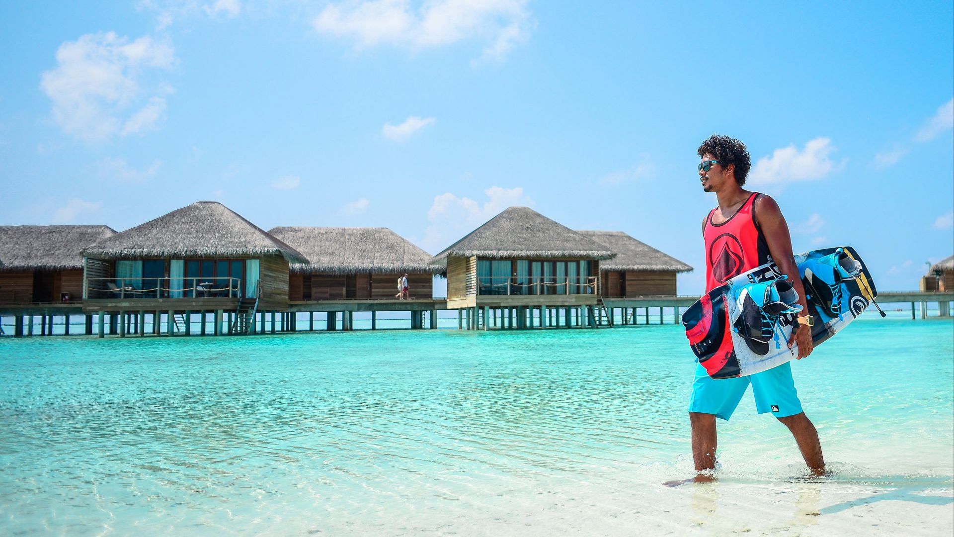 man in red tank top carrying wakeboard during daytime