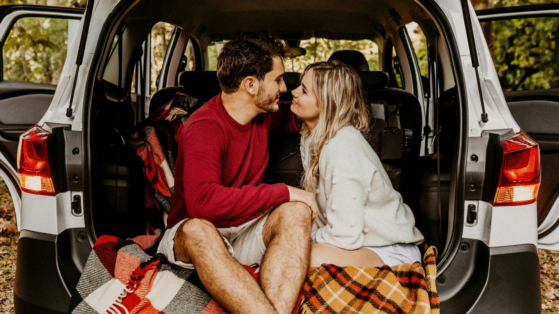 man and woman sitting on car's trunk
