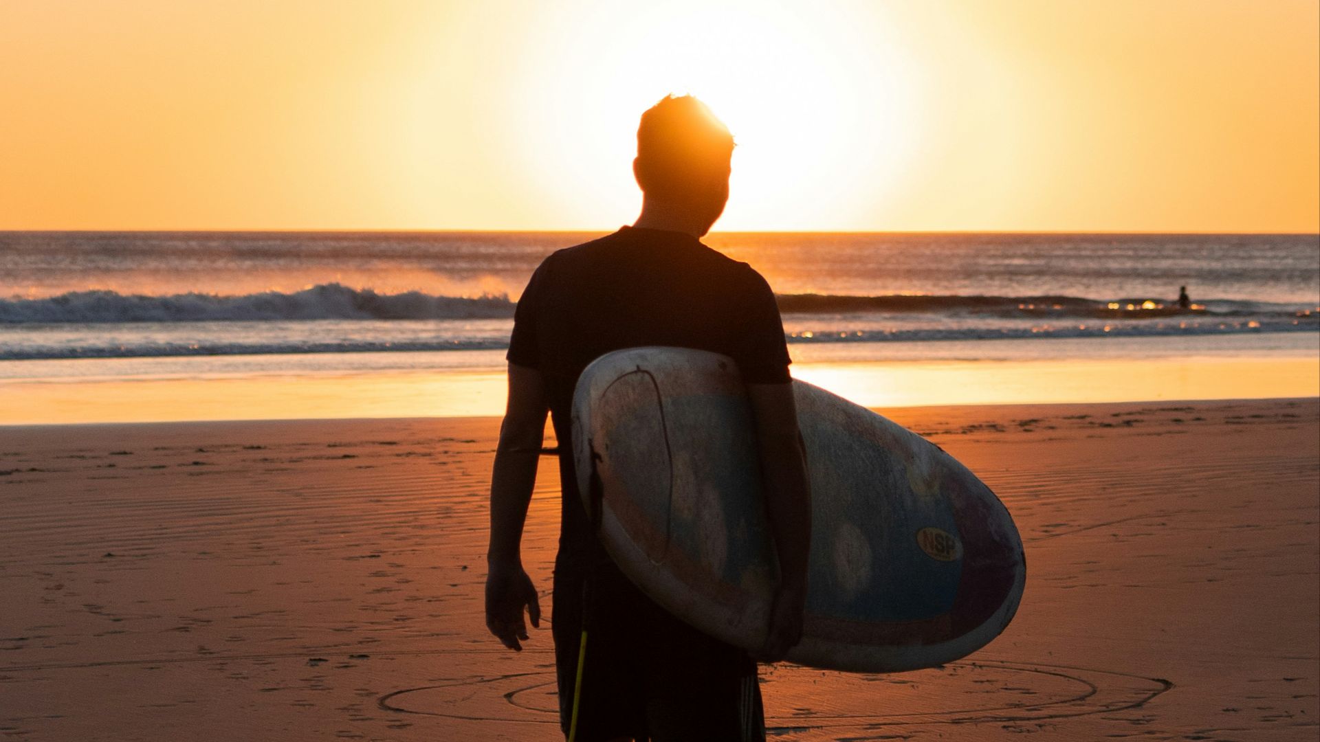 a man holding a surfboard on top of a sandy beach
