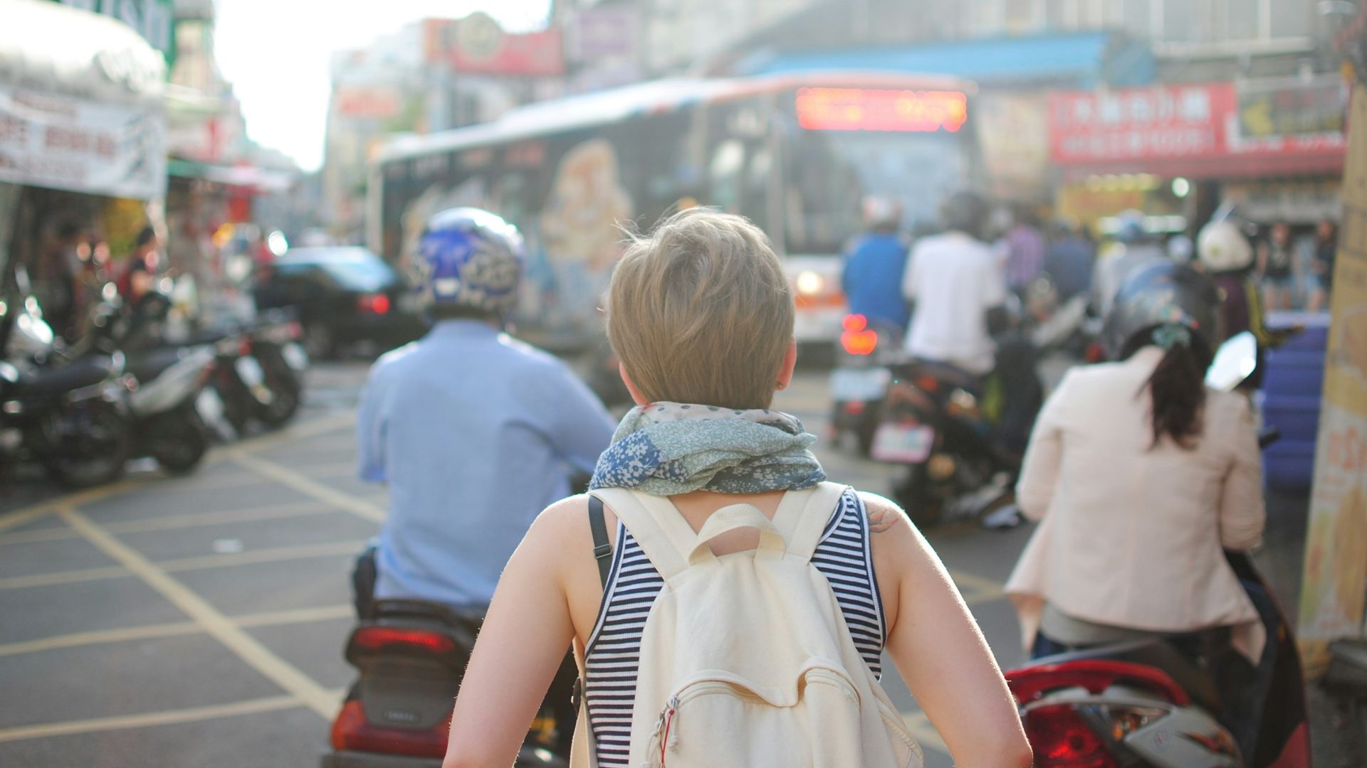 woman wearing backpack walking on road