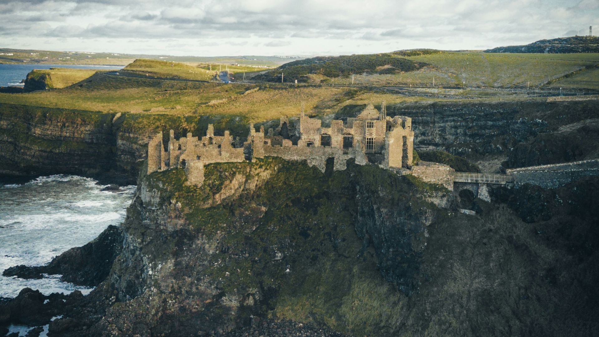 concrete castle on cliff near body of water during daytime