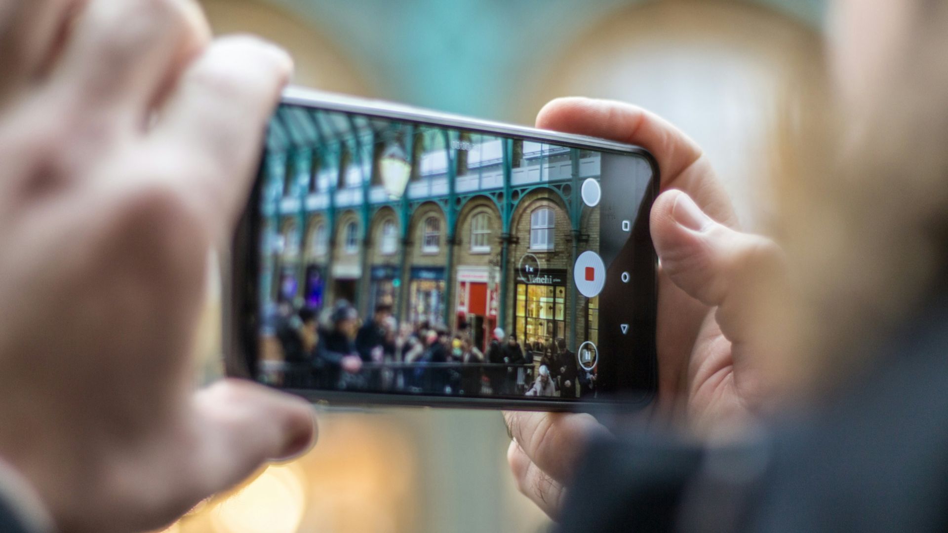 person holding smartphone taking video of people