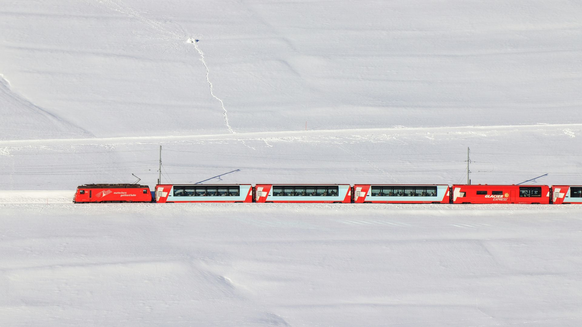 a red train traveling through a snow covered field