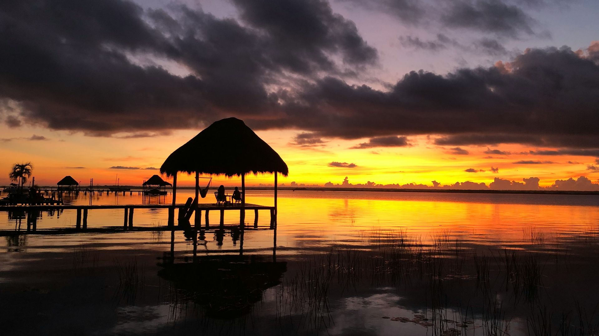 brown wooden beach house on body of water during sunset