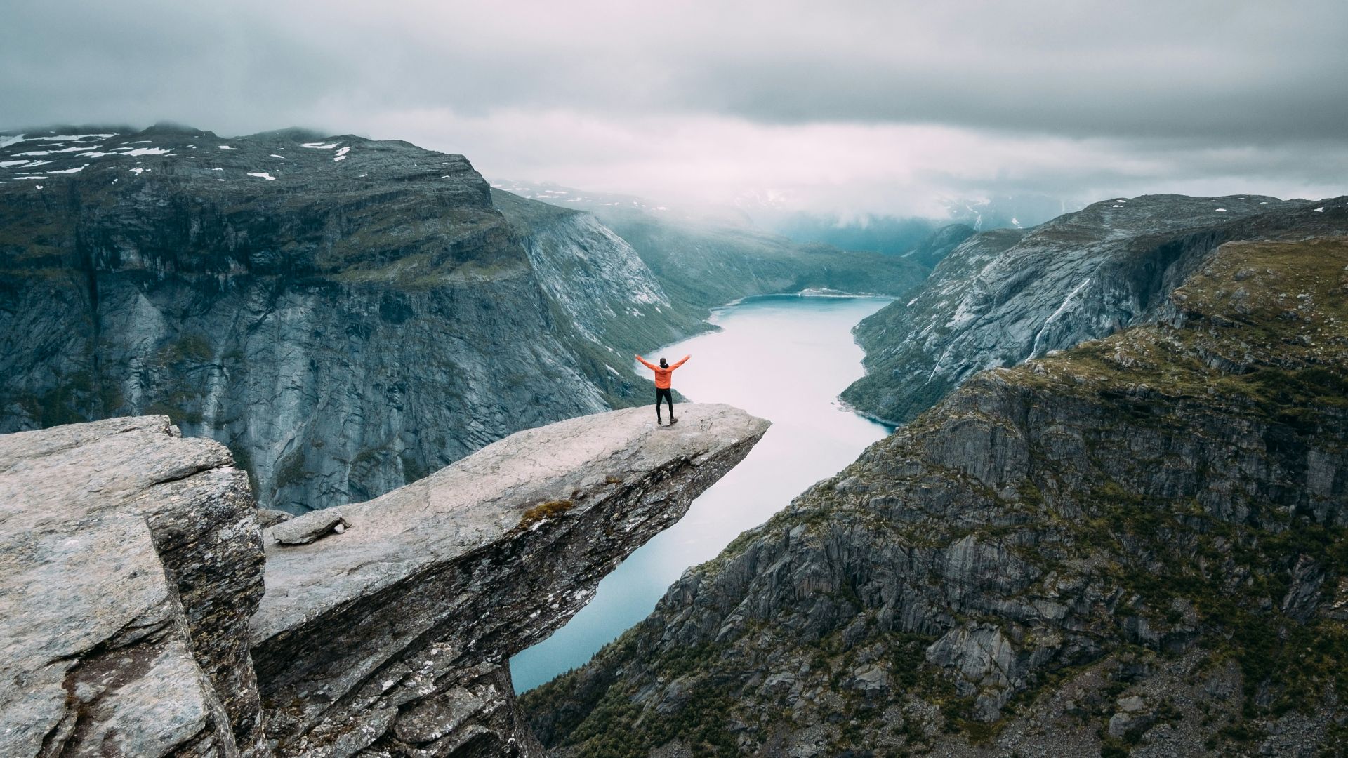 person standing on gray high-rise rock formation at daytime