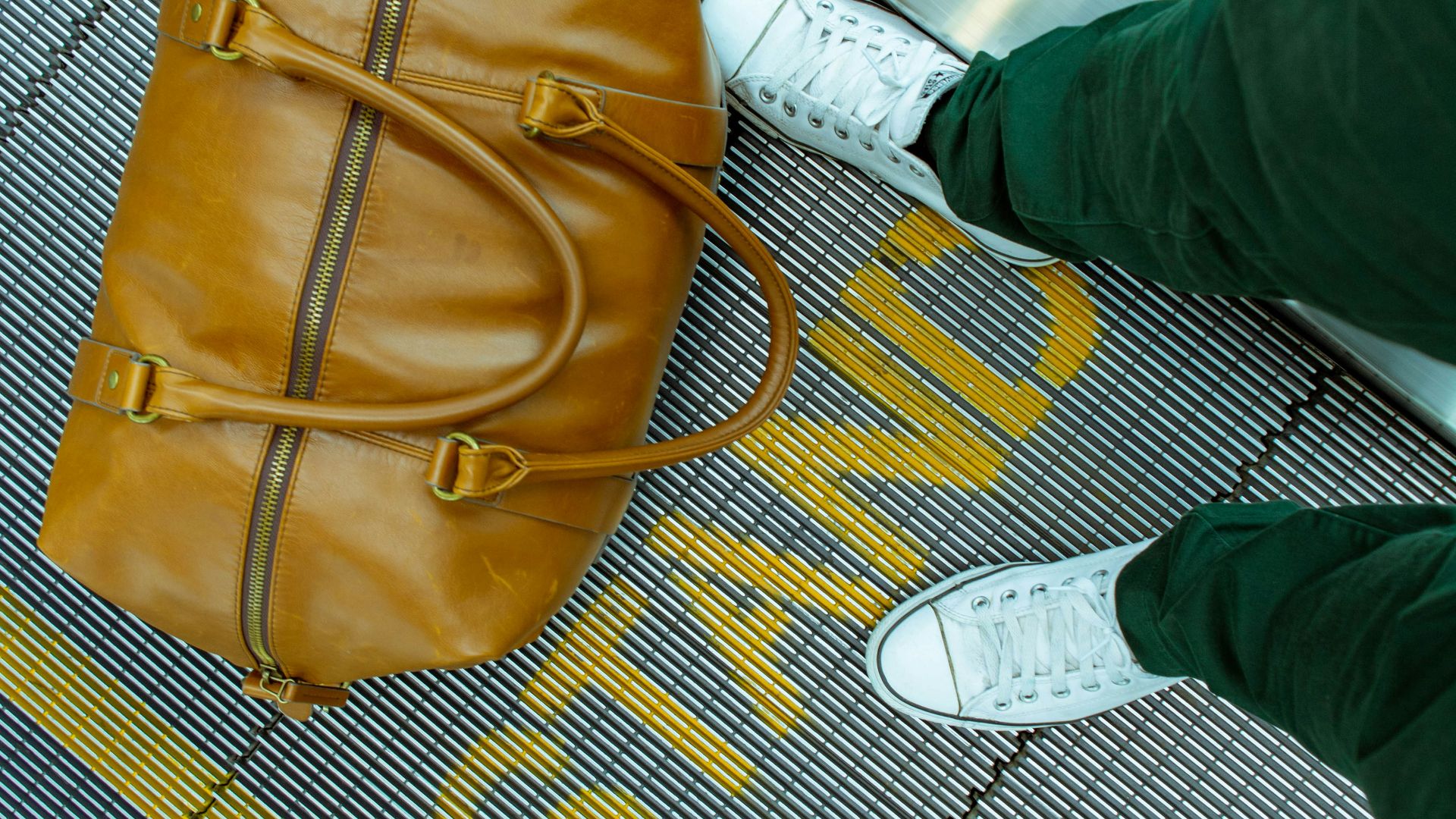 person stranding beside brown leather handbag