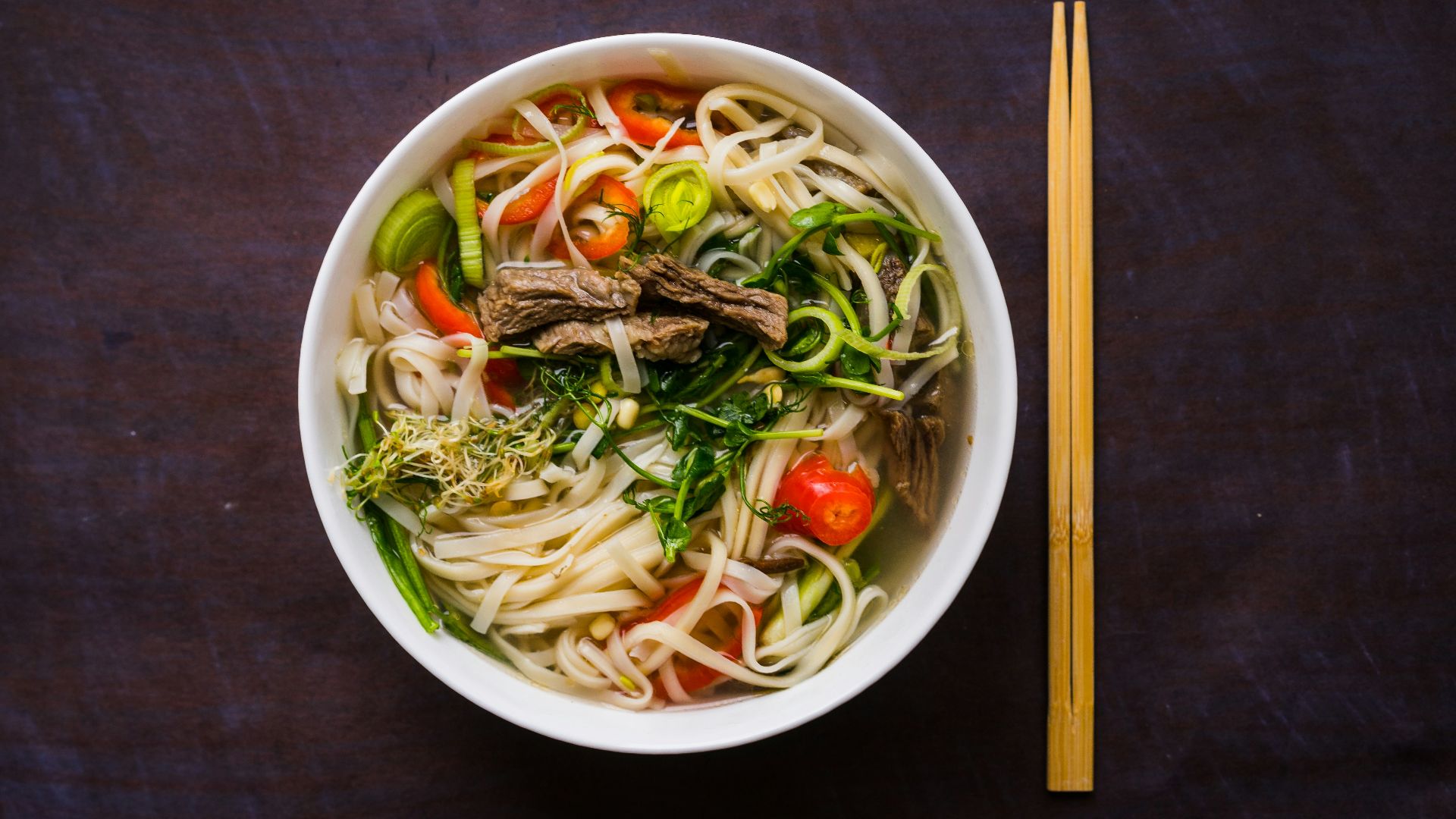 a bowl of noodle soup with chopsticks on the side
