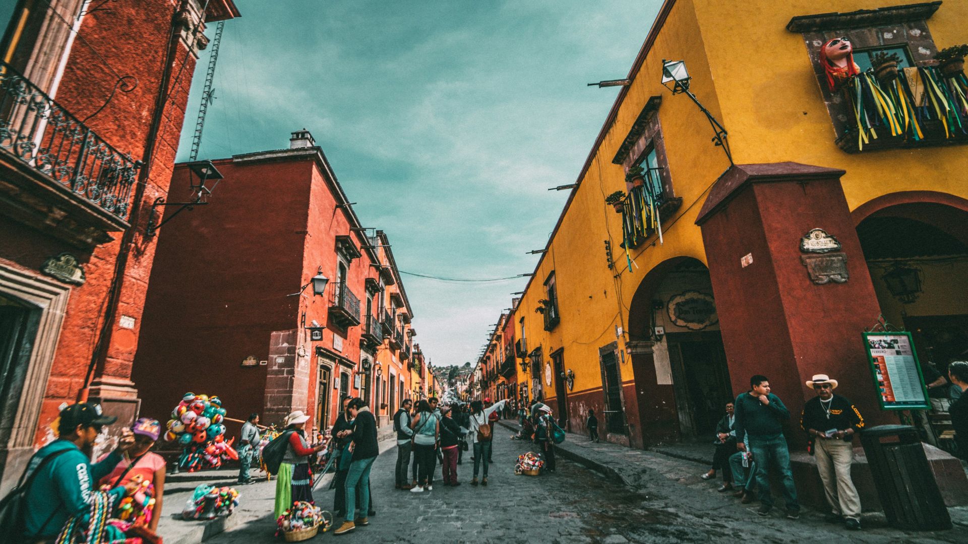 people standing on corner road near concrete buildings during daytime