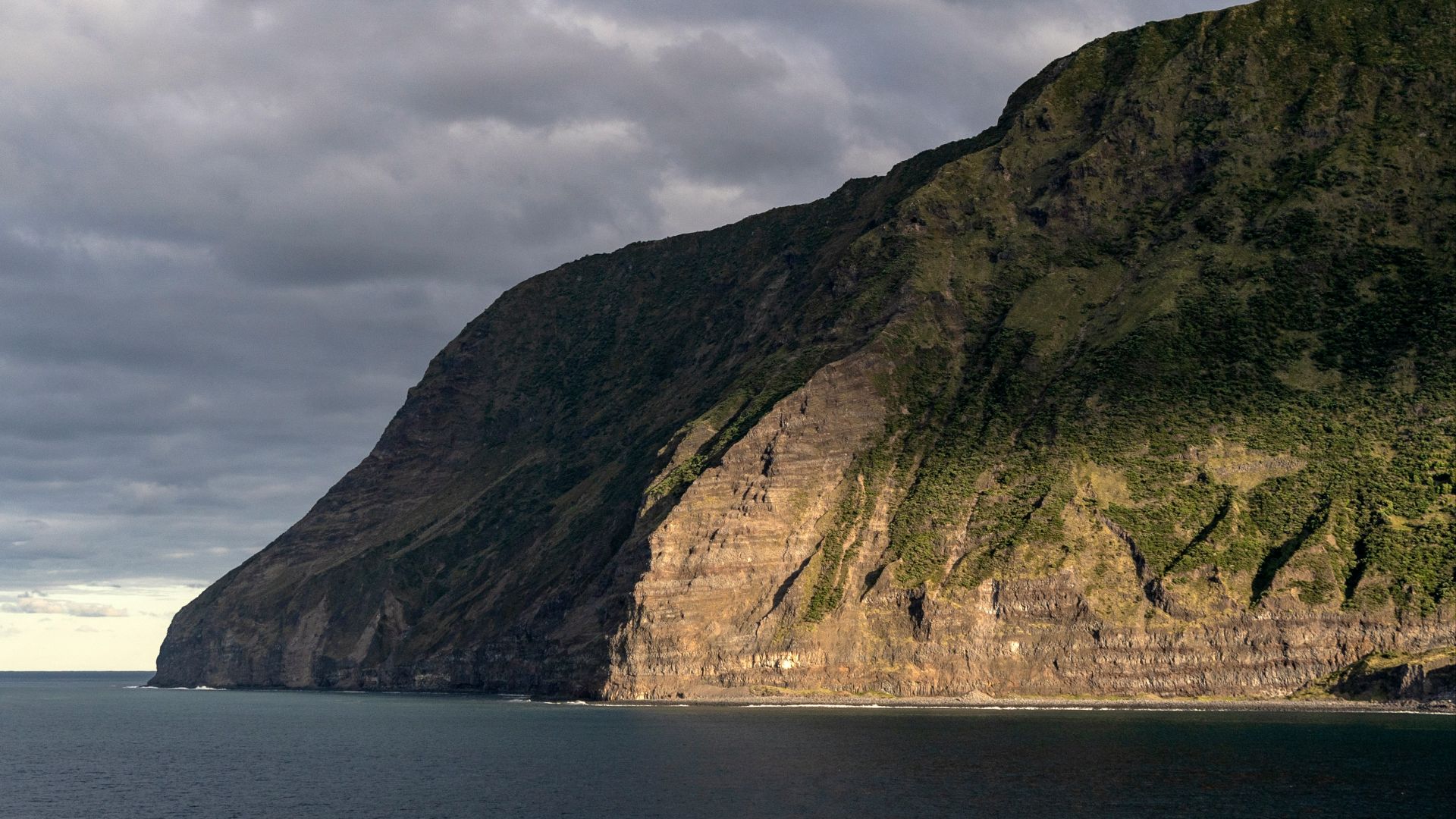 a large mountain sitting on the side of a body of water