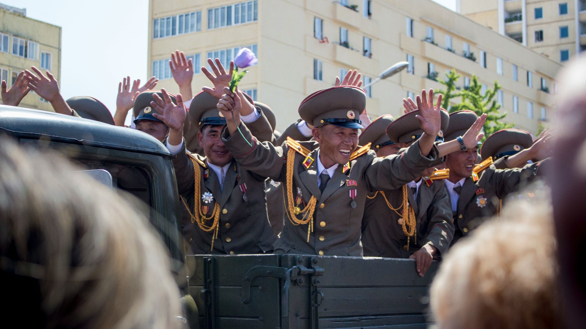 people in green and brown uniform standing near white concrete building during daytime
