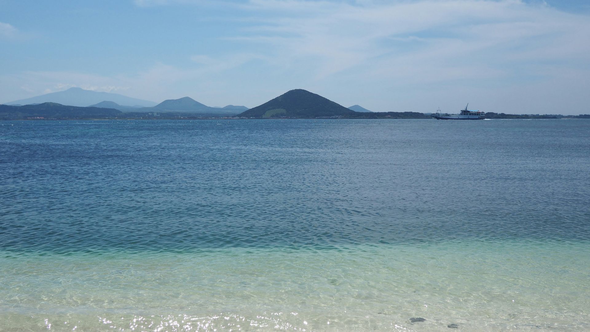 body of water near mountain under blue sky during daytime