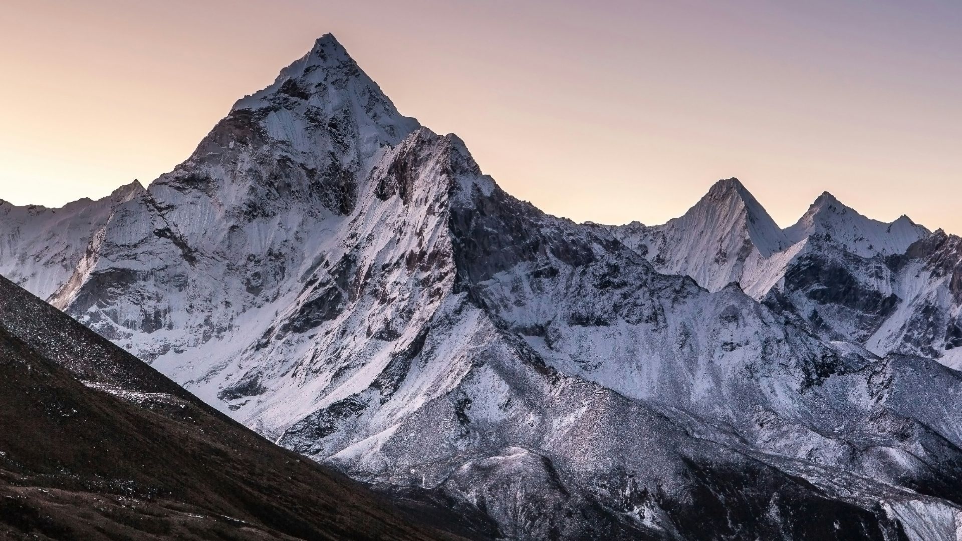 a mountain range covered in snow at sunset