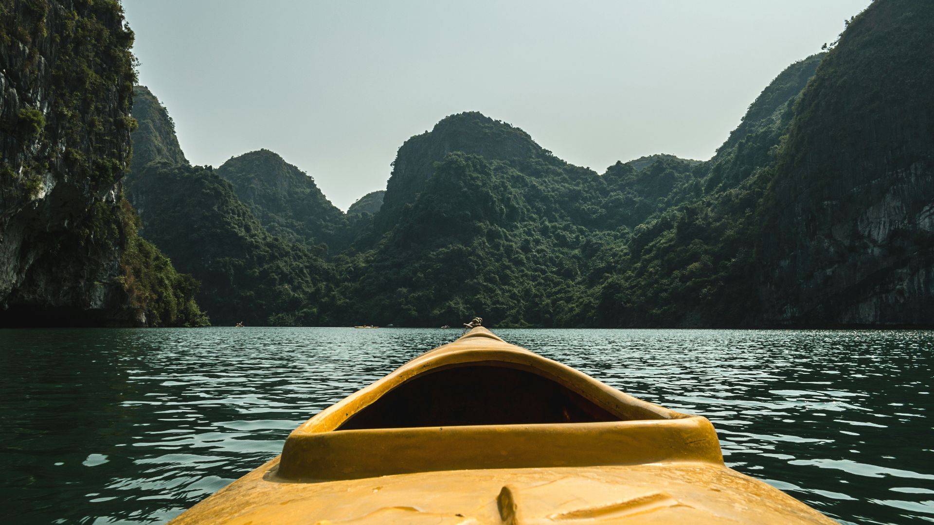 brown boat in the water surrounded by mountains
