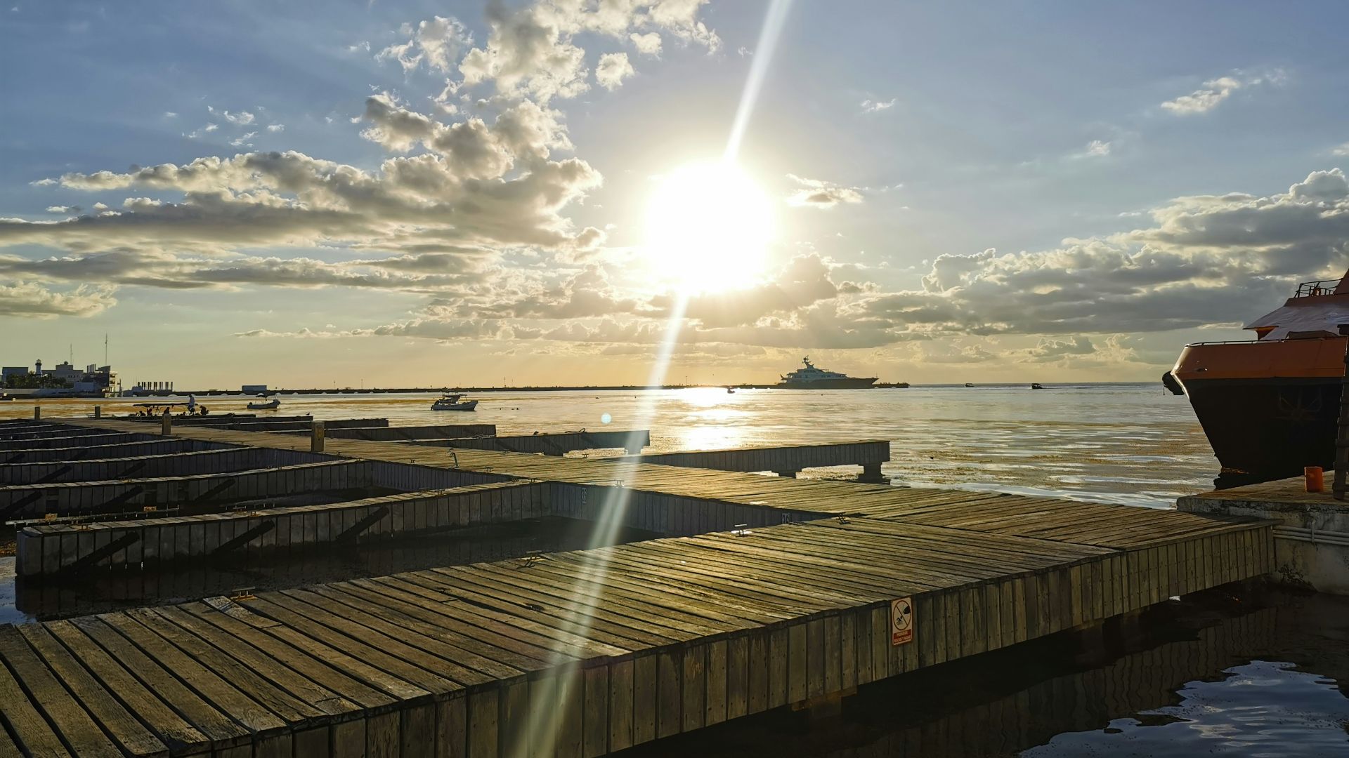 a dock with a boat and the sun in the background