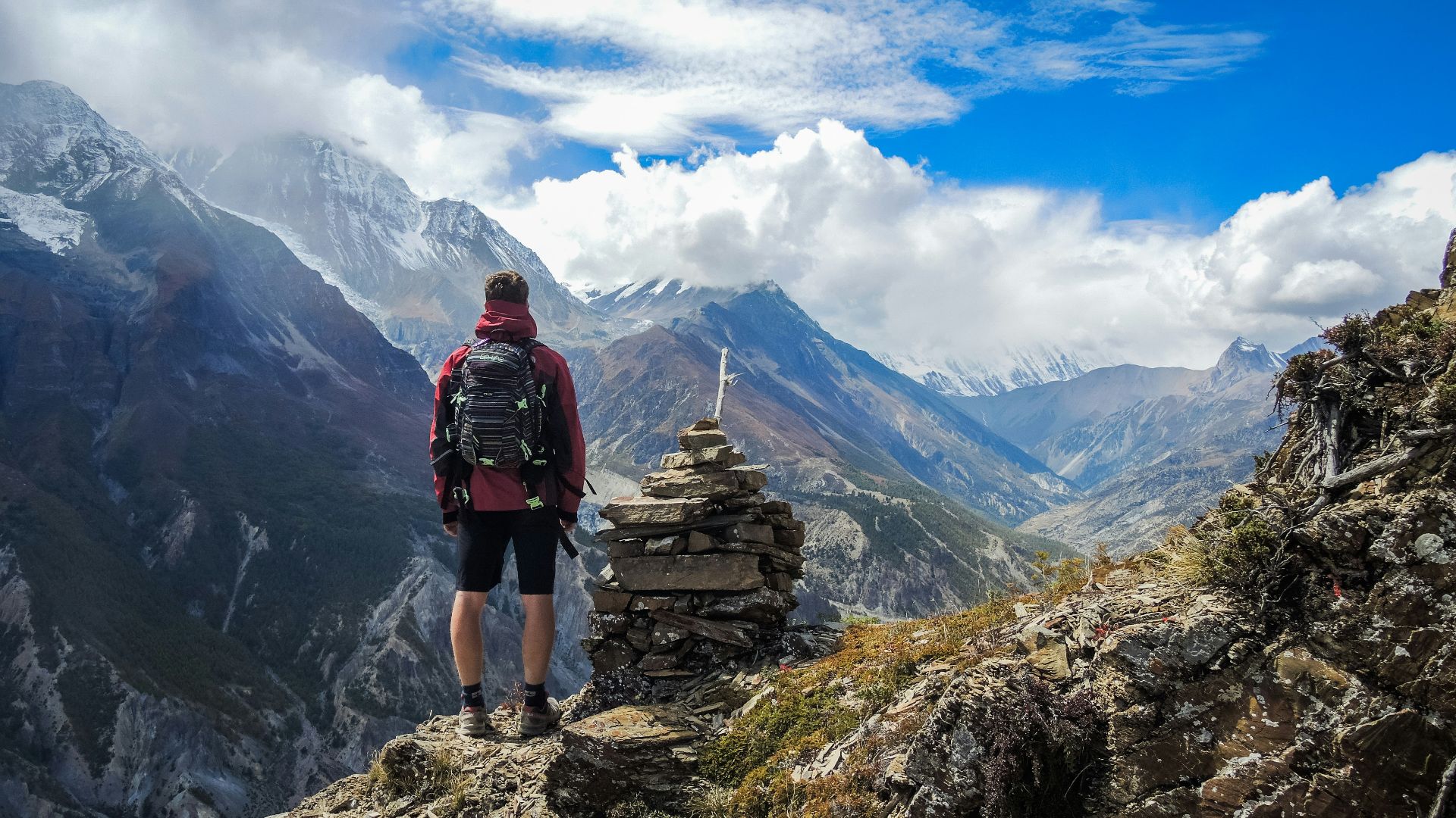 man standing on top of mountain beside cairn stones
