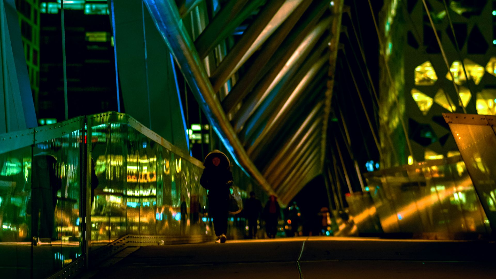 A person standing on a walkway in a city at night