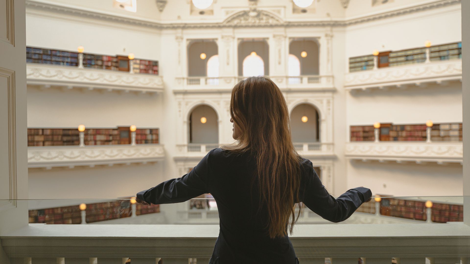 a woman in a black dress looking out a window