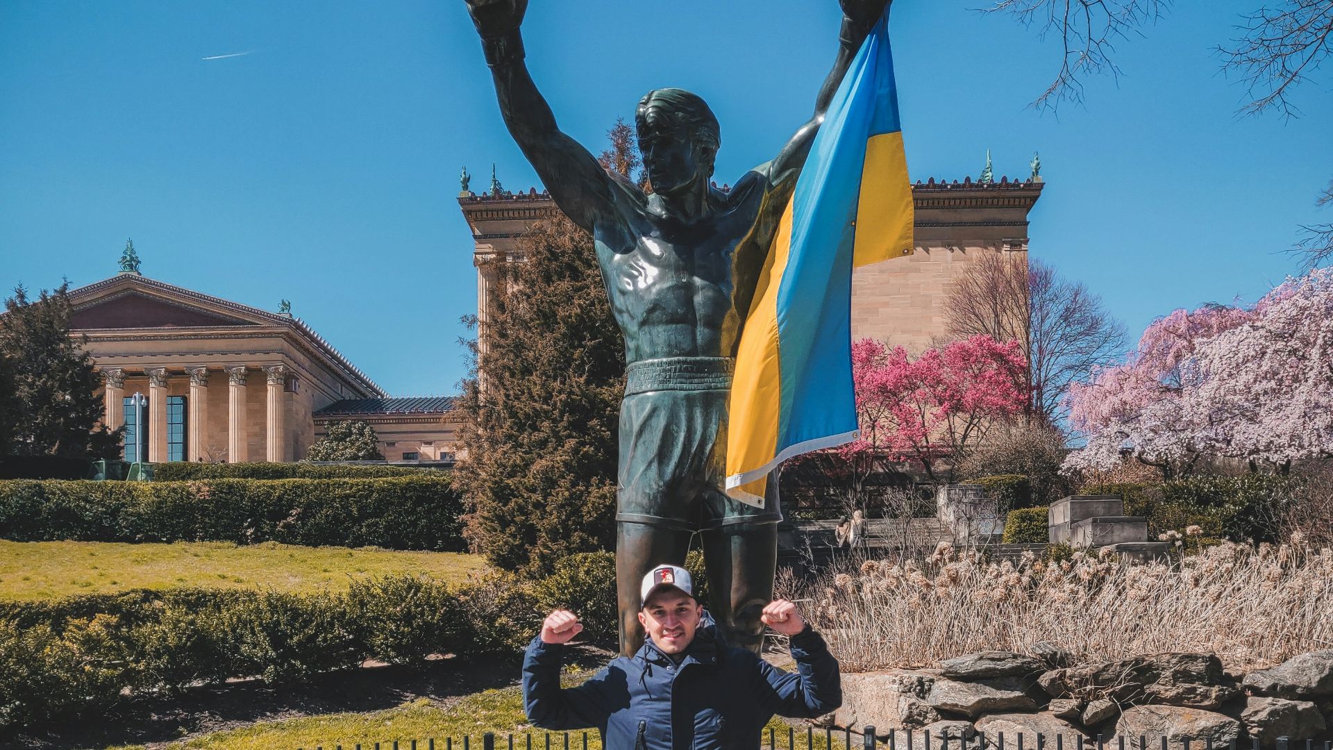 a man standing in front of a statue of a man holding a flag