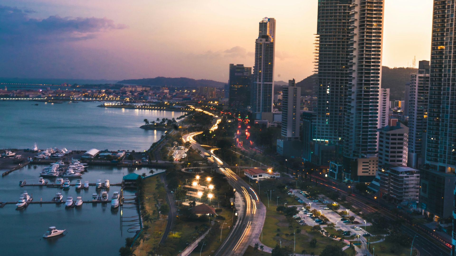high rise buildings near body of water in distant of mountain