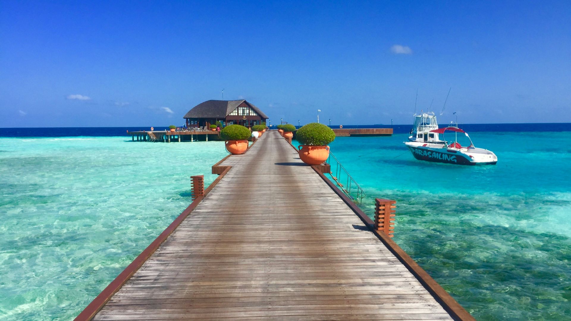brown wooden dock beside white motor boat