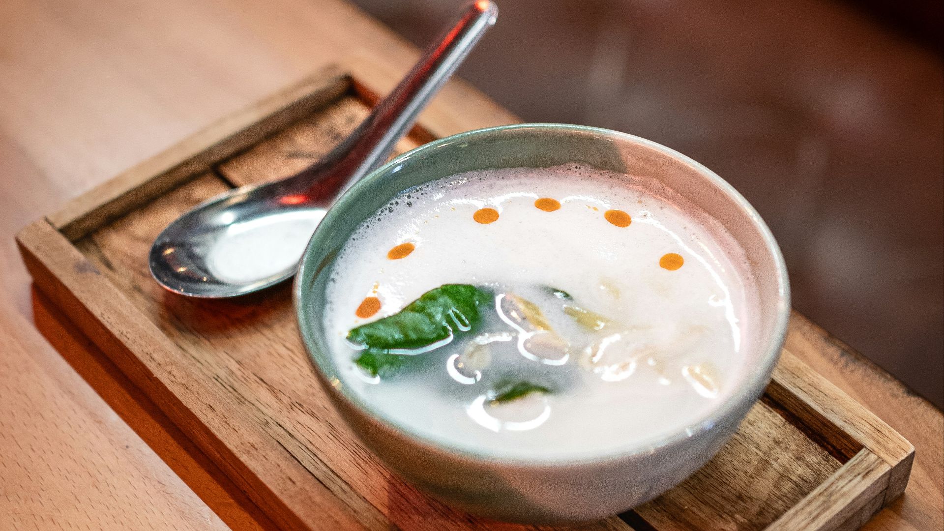 a bowl of milk and a spoon on a wooden tray