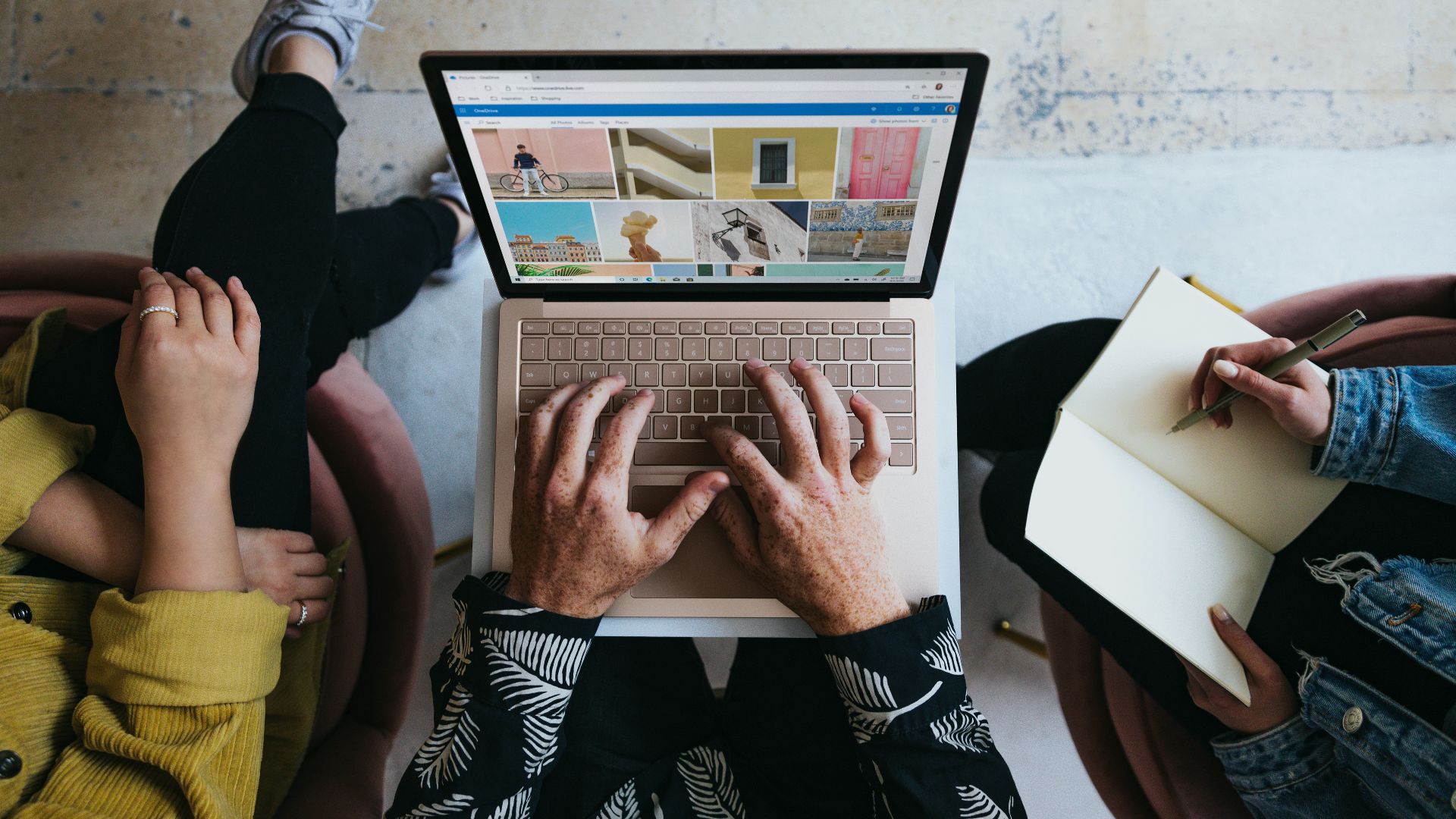 person using microsoft surface laptop on lap with two other people
