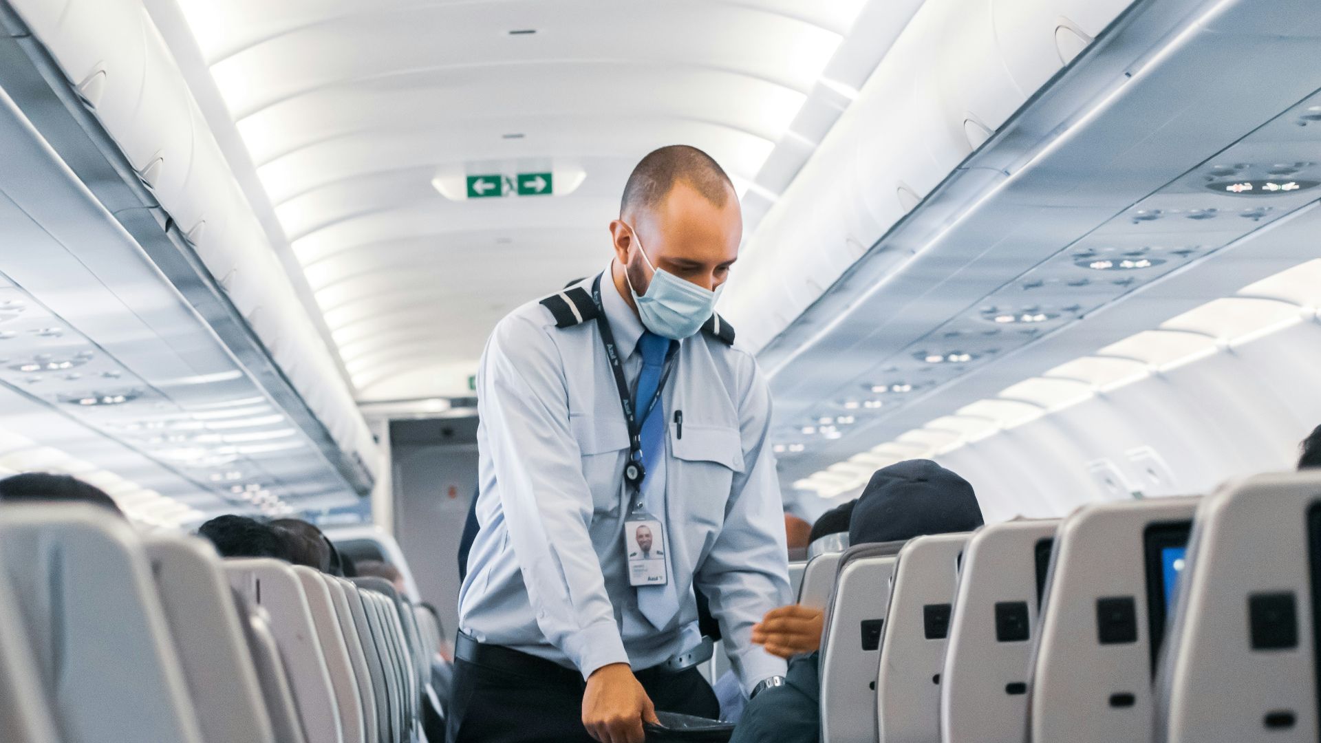 man in blue dress shirt standing in airplane