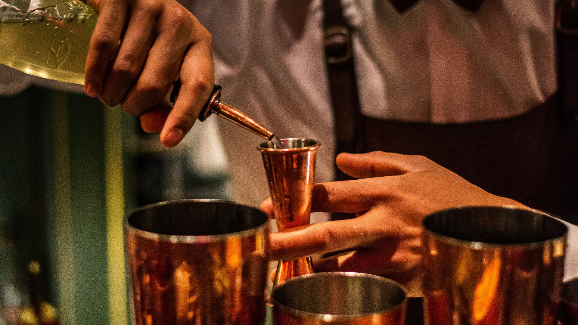 person pouring liquid in container from bottle