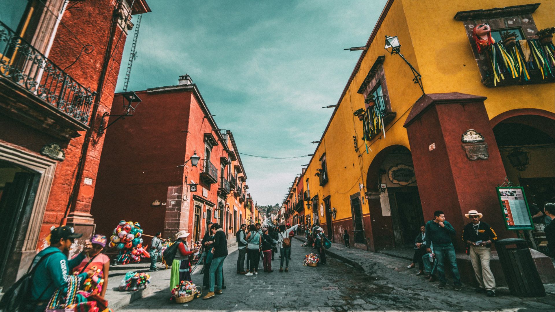 people standing on corner road near concrete buildings during daytime