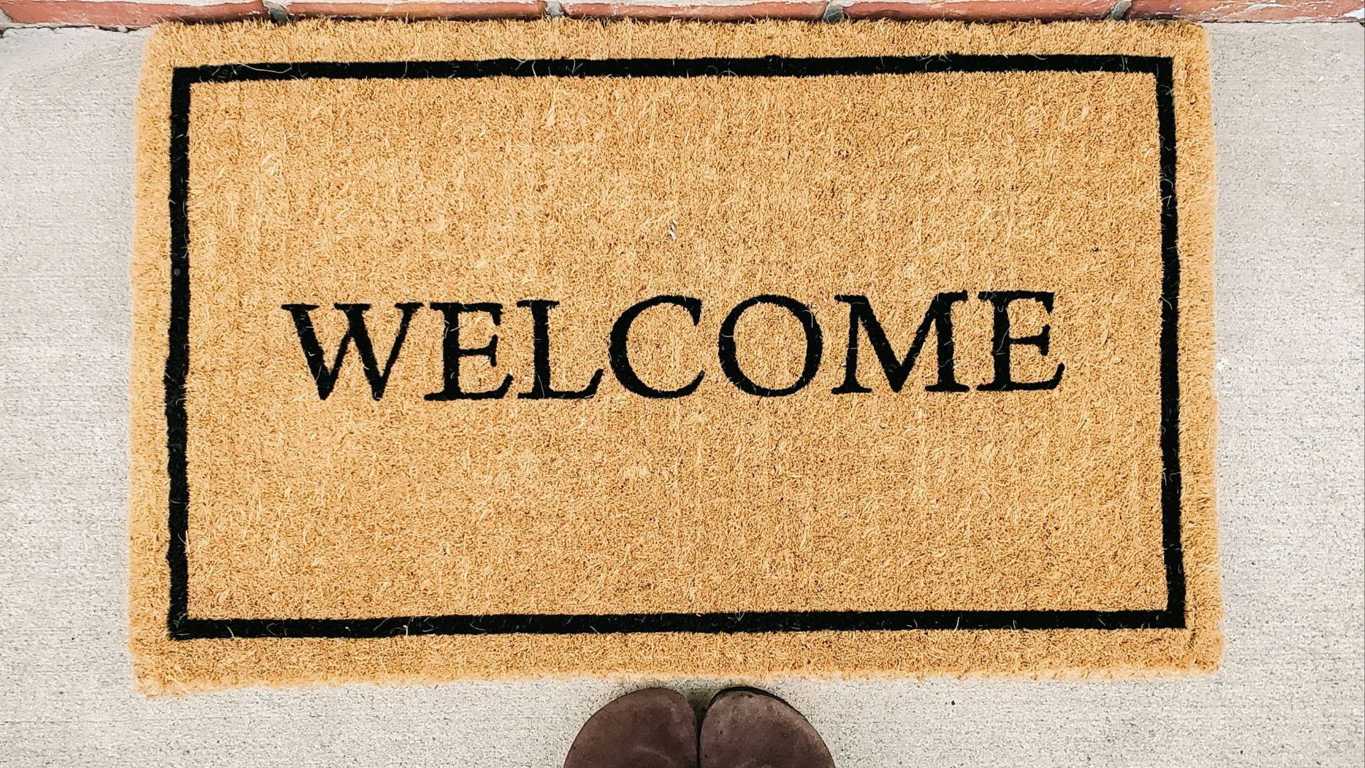 person in blue denim jeans standing on brown and black welcome area rug
